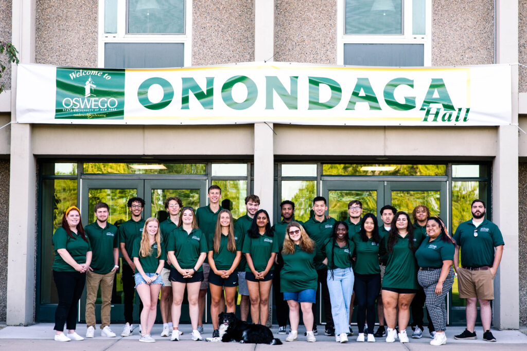 Front side of Onondaga Hall with 19 Resident Assistants, a dog, their Residence Hall Director, Assistant Hall Director, and Assistant Directos